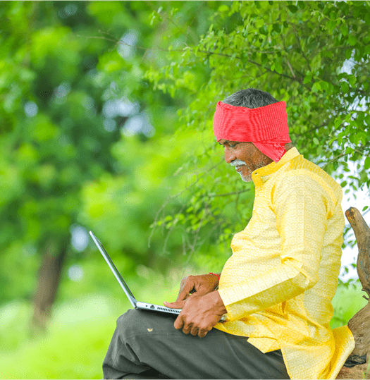 A man working on a laptop outdoors under trees